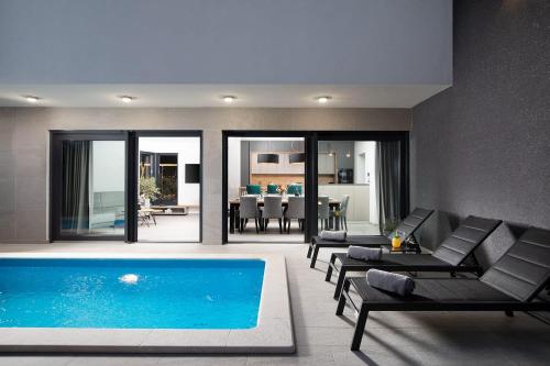 a living room with a swimming pool and furniture at Villa Tiki in Medulin for 16 person with heated pool & sauna only 1 km from the beach in Medulin