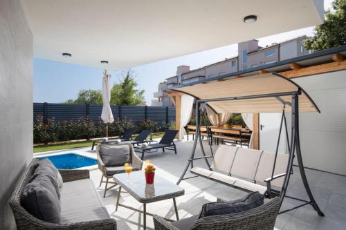 a patio with chairs and a table next to a swimming pool at Villa Tiki in Medulin for 16 person with heated pool & sauna only 1 km from the beach in Medulin