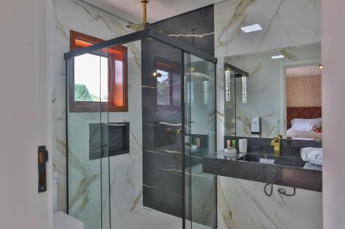 a bathroom with a glass shower and a sink at La Vita Pousada de Charme in Campos do Jordão