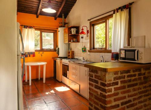 une cuisine avec des placards blancs et un mur en briques dans l'établissement Tu Apart en Bariloche 27, à San Carlos de Bariloche