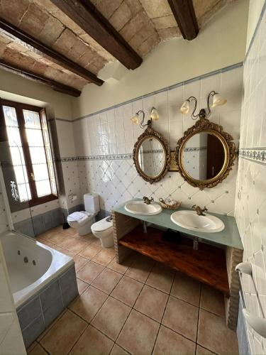 a bathroom with two sinks and a tub and a toilet at Hotel De La Villa in Rubielos de Mora