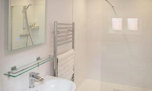 uma casa de banho branca com um lavatório e um chuveiro em Eastholme, style and luxury in Southwold, Suffolk em Southwold