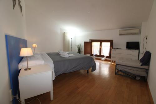1 dormitorio con 1 cama, 1 silla y TV en La Risalita, en Siena