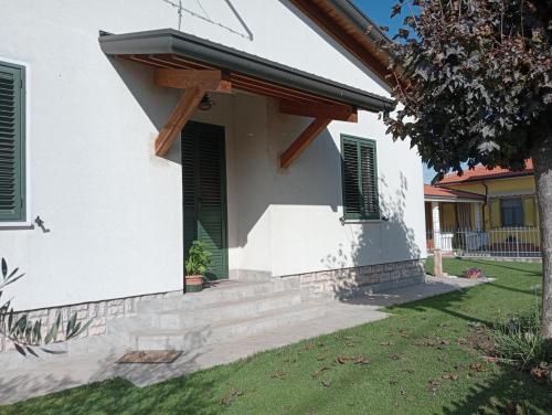 a white house with green shutters and a porch at Casa Il giardino in Ca degli Oppi