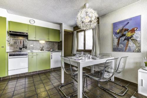 a kitchen with green cabinets and a white table and chairs at Appartement Diana 33 in La Tzoumaz