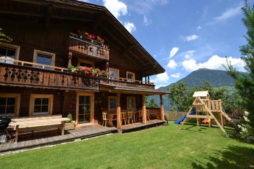 una casa de madera con un parque infantil delante de ella en Chalets & Apartments Wachterhof, en Kaltenbach