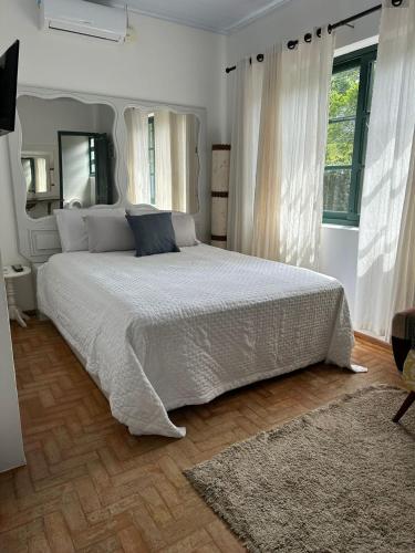 a bedroom with a large bed with white sheets at Mala & Tudo Pousada in Torres