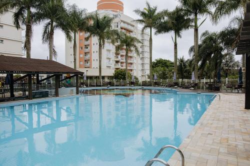 une grande piscine avec des palmiers en face d'un bâtiment dans l'établissement Ap 3 quartos em home club - Beto Carrero/Penha, à Penha