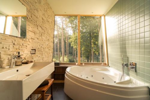a bathroom with a large tub and a window at Tree Inn - Das Baumhaushotel in Dörverden