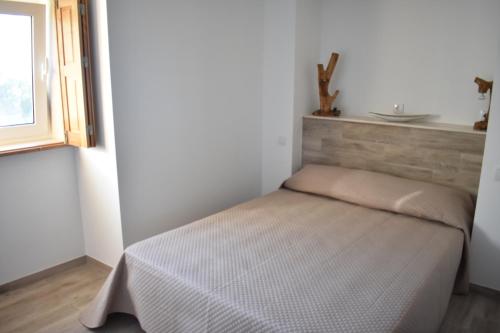 a small bedroom with a bed in a room with a window at Casa Botica - Gerês Country House in Terras de Bouro