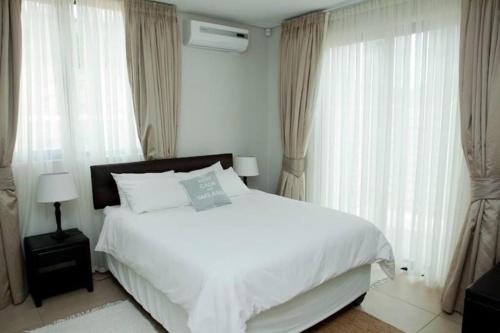 a bedroom with a large white bed and windows at Home away from home in Windhoek