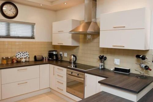 a kitchen with white cabinets and a clock on the wall at Home away from home in Windhoek