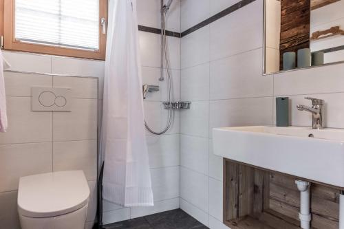 Un baño blanco con lavabo e inodoro. en Eigerhome - The Cottage mit Wellness - GRIWA RENT AG, en Grindelwald