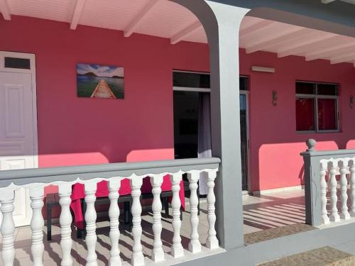 a pink house with a white picket fence at Terrasse des Manguiers : logement indépendant in Pointe-Noire