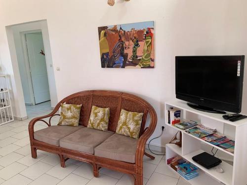 a living room with a couch and a flat screen tv at Terrasse des Manguiers : logement indépendant in Pointe-Noire