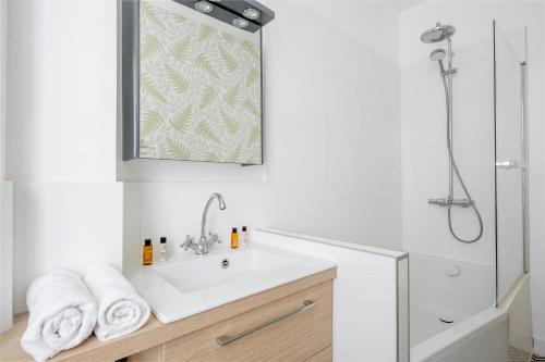 une salle de bain blanche avec un lavabo et une douche dans l'établissement Veeve - Flowers from Paris, à Paris