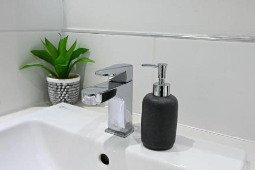 a black soap dispenser sitting on a bathroom sink at Contemporary 1 Bed Apartment in Bedford