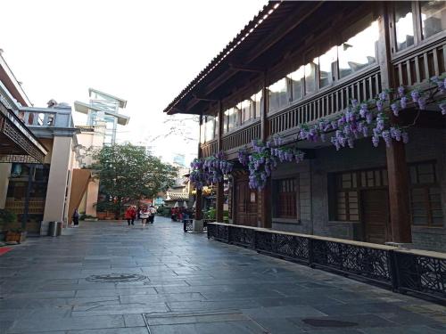 a street with purple flowers hanging from a building at Annie Apartment - only 120 metres from Metro Line 2 Exit B of Chuanxingulou in Kunming
