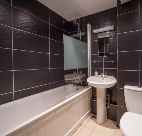 ein Badezimmer mit einem Waschbecken, einer Badewanne und einem WC in der Unterkunft The Rodney Hotel in Bristol