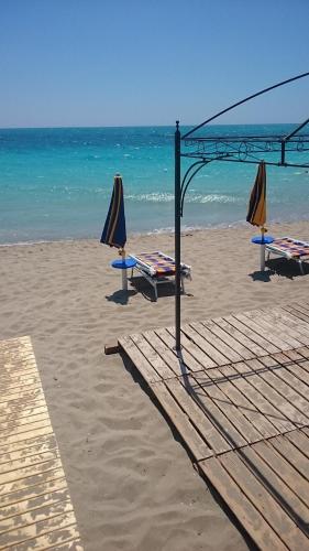 ガリポリにあるGallipoli Lungomareの海辺のビーチに傘とテーブル2本