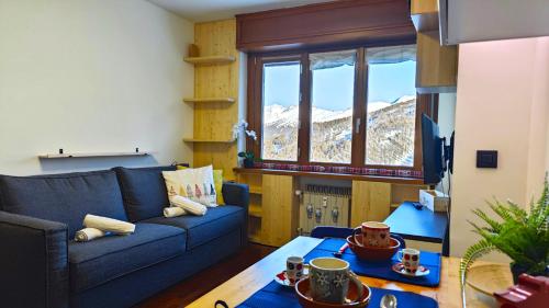 uma sala de estar com um sofá azul e uma mesa em Hostdomus - Flowers Residence em Sestriere