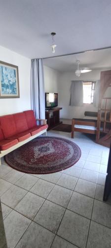 a living room with a red couch and a tv at Casa e quintal exclusivo Meu Xodó- rota da ferradura em Guarapari- Praia e montanha- até 4 pessoas in Guarapari
