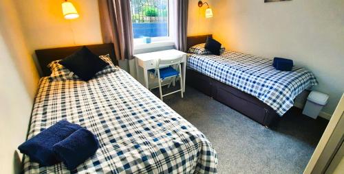 a room with two beds and a desk and a window at Tom's Place in Kirkcudbright