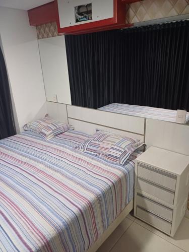 a small bedroom with a bed with striped sheets at Brookfield Tower in Goiânia