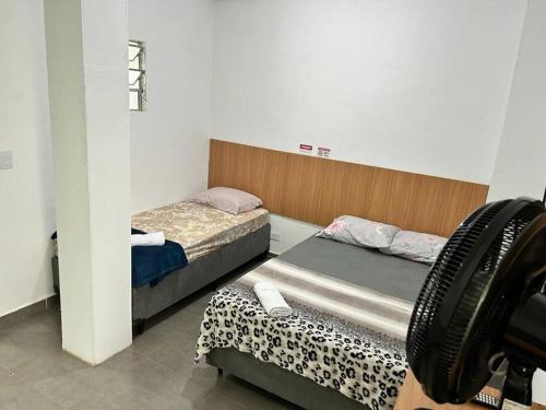 two twin beds in a room with a camera at Studio mobiliado em São Paulo Vila Guilherme - Expo Center Norte in Sao Paulo