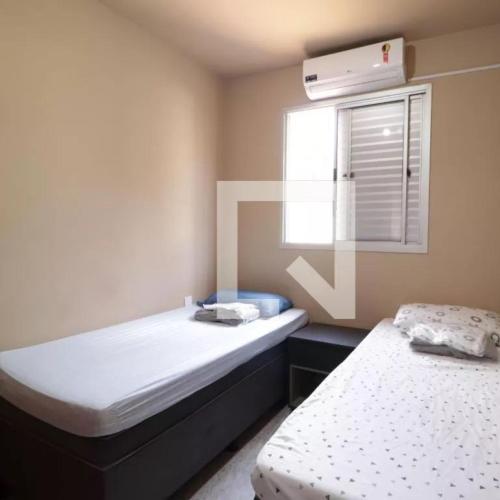 two beds in a small room with a window at Aptos 1 quarto Ar Saraiva in Uberlândia