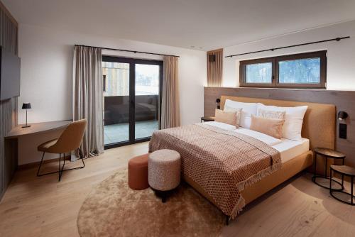 a bedroom with a large bed with a desk and a desk at Alpin Residenzen Eichenheim Aurach bei Kitzbühel by Alpina-Holiday in Aurach bei Kitzbuhel