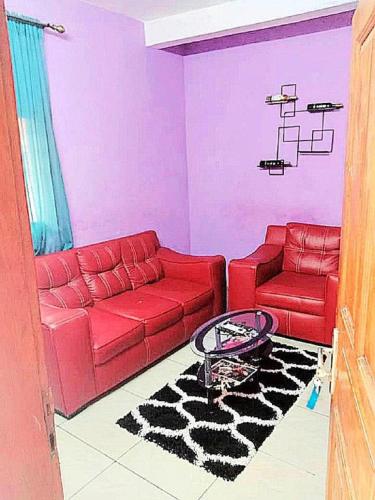 a living room with a red couch and a chair at Residence Sighaka - Studio Meublé VIP avec WiFi, Gardien, Parking in Douala
