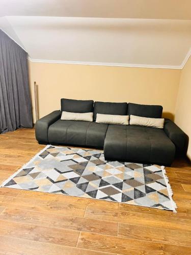 a black couch in a living room with a rug at Golden Lemon in Mizhhirʼʼya
