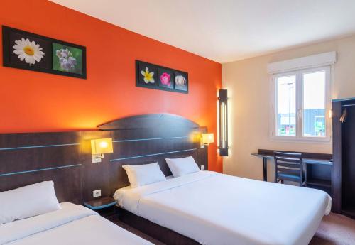 two beds in a hotel room with an orange wall at B&B HOTEL Agen Castelculier in Castelculier