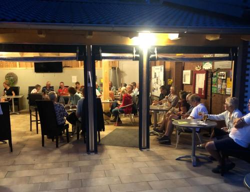 grupa ludzi siedzących przy stolikach w restauracji w obiekcie Camping Sonnenberg w mieście Faßberg