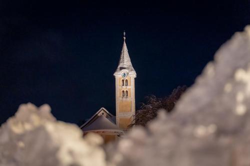 a church steeple with a clock tower at night at Ferienhaus am Burgsee in Ladis