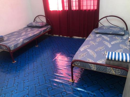 Duas camas num quarto com piso azul em Easah Homestay Malacca em Malaca