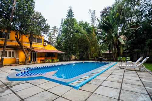 una piscina con 2 tumbonas junto a una casa en Lemon Zest Oasis By JadeCaps Pvt Pool 6BHK Goa en Nuvem