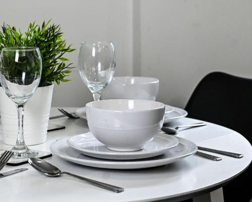 a table with plates and wine glasses on it at Chic 1 Bedroom Flat in Bedford