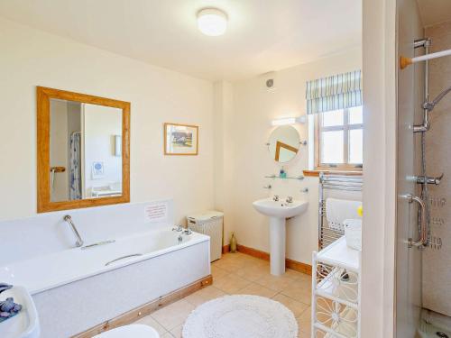 uma casa de banho com uma banheira, um lavatório e um espelho. em 3 Bed in Ardvasar CA071 em Aird of Sleat