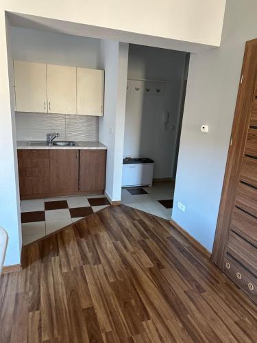 an empty room with a kitchen with wooden floors at Apartament Wałbrzych in Wałbrzych