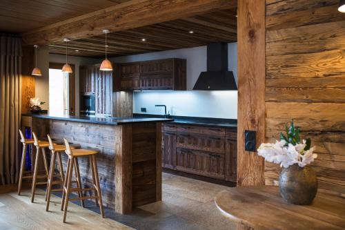 une cuisine avec des armoires en bois et un comptoir avec une table dans l'établissement Les Chalets PVG, à La Clusaz