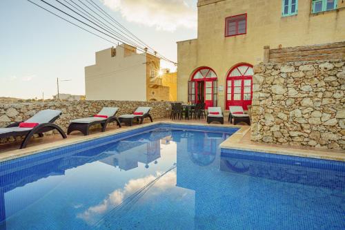 a swimming pool with chairs next to a building at Amaryllis Holiday Home in Qala
