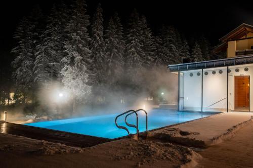 a swimming pool at night with snow covered trees at Hotel Majon Miramonti in Canazei