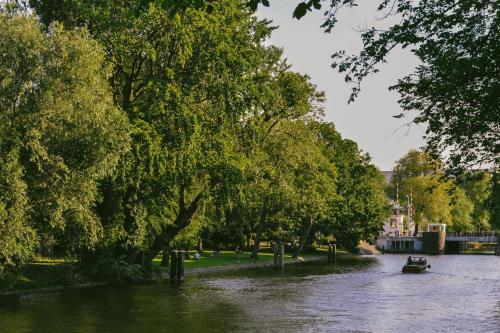 a boat on a river with trees on the side at Amsterdam Lake Hotel in Badhoevedorp