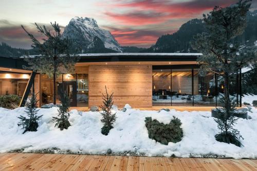 a house in the snow with a mountain in the background at Hotel Majon Miramonti in Canazei