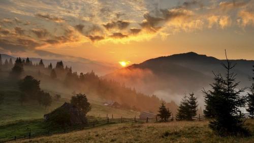 a sunset in a field with fog in the mountains at Рандеву in Slavske