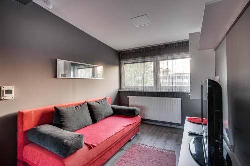 a living room with a red couch and a tv at Magdi Vendégház in Celldömölk