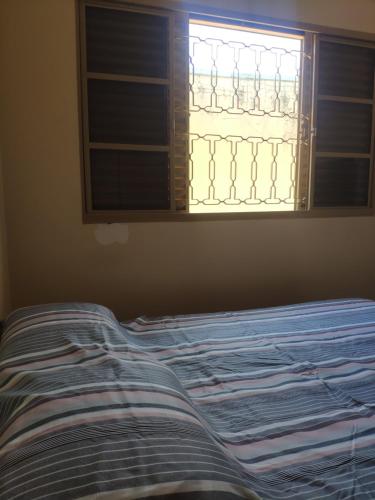 Cama en habitación con ventana en Pousadinha Sophia Verde, en Goiânia