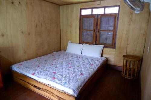 a bed in a wooden room with a window at Song Lao Guesthouse in Thakhek